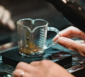 Measuring cup under espresso machine handle